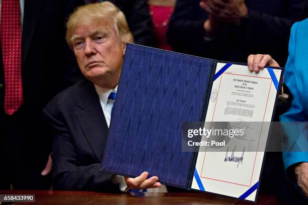 President Donald Trump holds up H.J. Res. 57, which overturns a rule on school accountability standards that are part of the Every Student Succeeds...