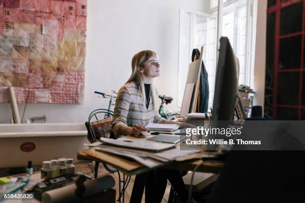 creative woman looking at computer screen - blonde attraction stock-fotos und bilder