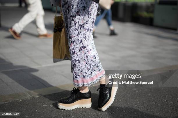 Guest is seen on the street wearing a black leather jacket, white/black/pink skirt, and black/tan/white shoes during Tokyo Fashion Week on March 24,...