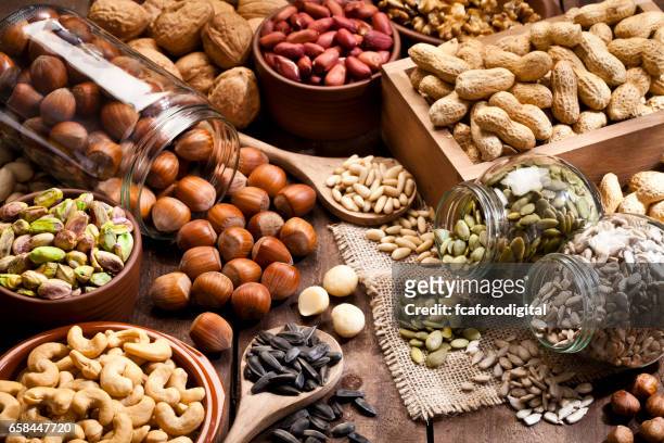 assortment of nuts on rustic wood table. - seed imagens e fotografias de stock