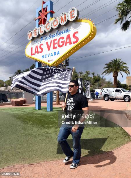 Oakland Raiders fan Matt Gutierrez of Nevada carries a Raiders flag in front of the Welcome to Fabulous Las Vegas sign after National Football League...