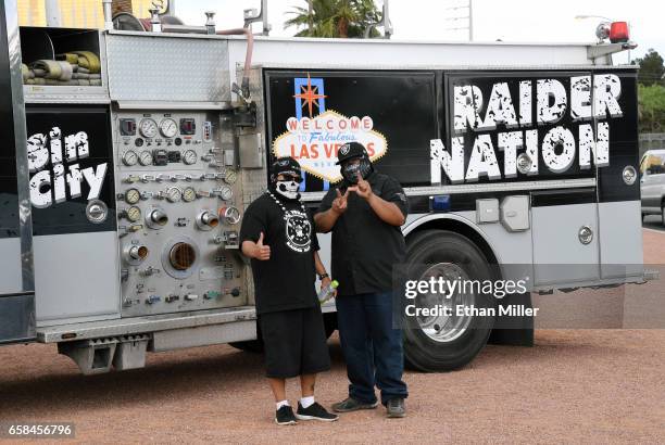 Oakland Raiders fans Tony Maldonado and his son Nick Maldonado, both of Nevada, pose in front of a fire engine emblazoned with Raiders logos near the...