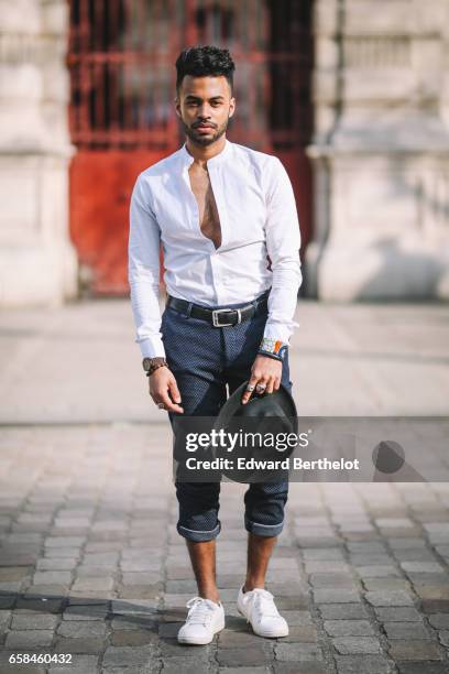 Theo Kimbaloula, fashion blogger, wears an Asos white collarless shirt, Sand Copenhagen cropped pants, a Time for Wood watch, white sneakers shoes,...