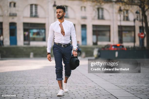 Theo Kimbaloula, fashion blogger, wears an Asos white collarless shirt, Sand Copenhagen cropped pants, a Time for Wood watch, white sneakers shoes,...