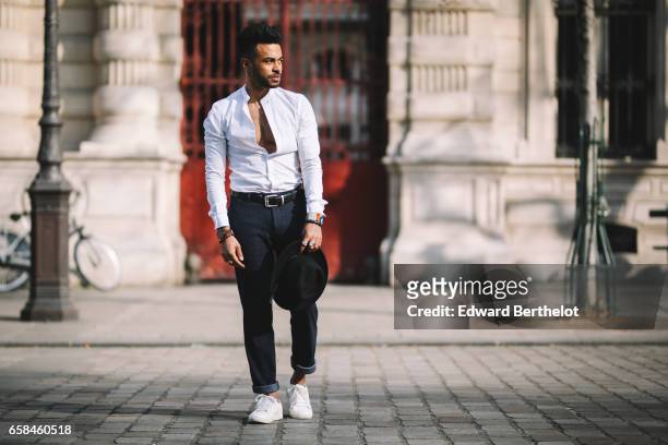 Theo Kimbaloula, fashion blogger, wears an Asos white collarless shirt, Sand Copenhagen cropped pants, a Time for Wood watch, white sneakers shoes,...