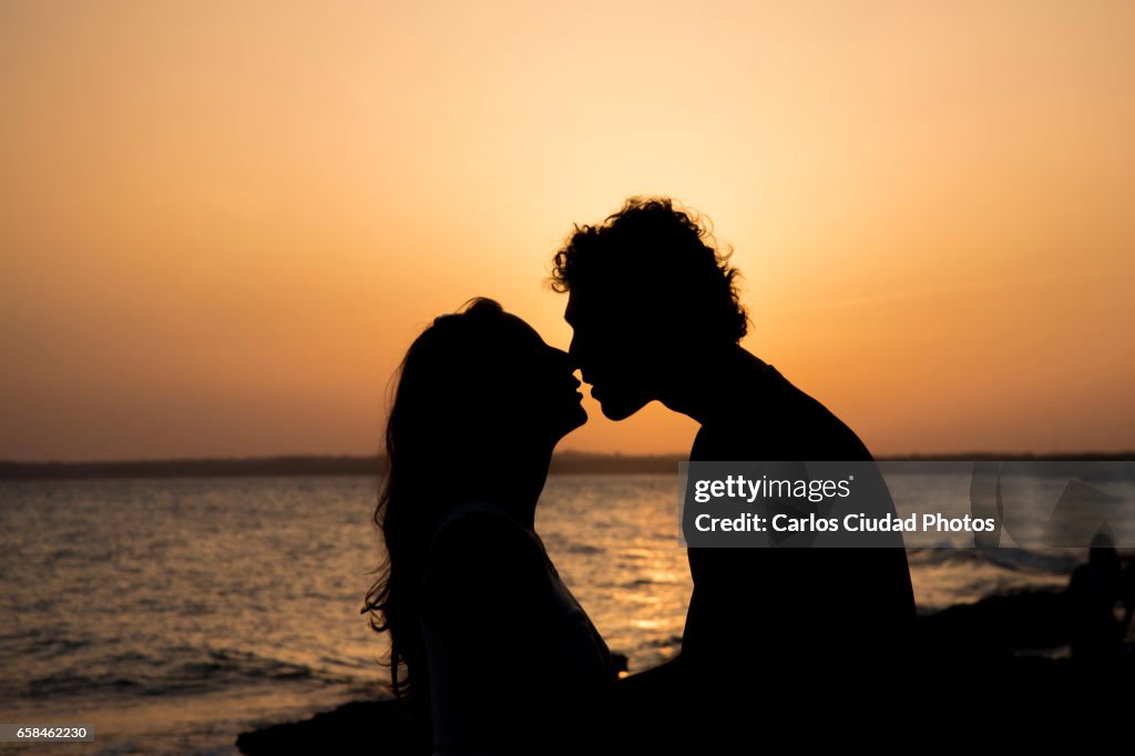 Silhouette of couple kissing at sunset on the beach