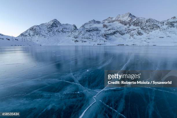 the lights of dusk on frozen lago bianco switzerland - lago reflection stockfoto's en -beelden