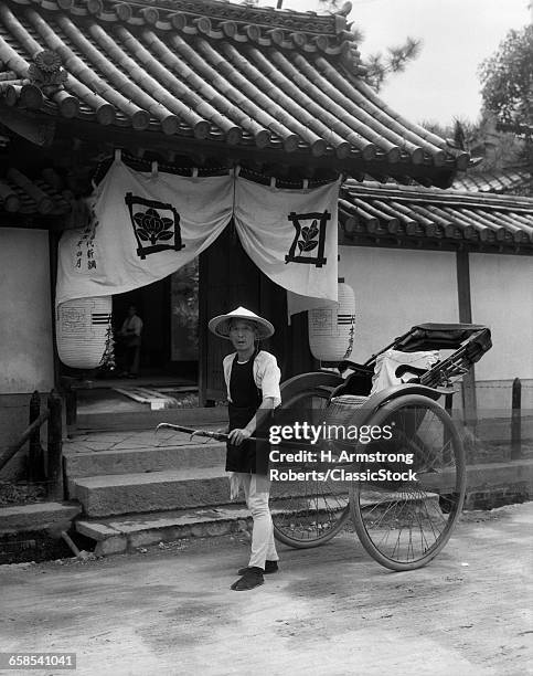 1930s JAPANESE MAN WORKER LOOKING AT CAMERA PULLING RICKSHAW RIKSHA JINRIKSHA STAND BEFORE TEMPLE IN KOBE JAPAN