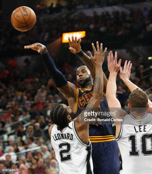 LeBron James of the Cleveland Cavaliers passes off in front of Kawhi Leonard of the San Antonio Spurs at AT&T Center on March 27, 2017 in San...