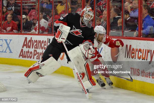 Detroit Red Wings Winger Riley Sheahan skates around Carolina Hurricanes Goalie Eddie Lack as he plays the puck in the trapezoid in a game between...