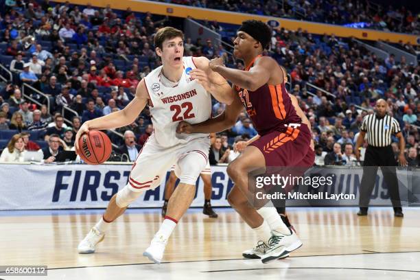 Ethan Happ of the Wisconsin Badgers dribbles around Zach LeDay of the Virginia Tech Hokies during the First Round of the NCAA Basketball Tournament...