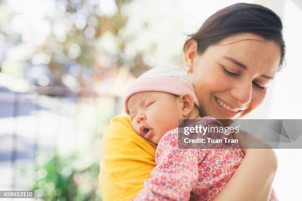 mother carrying sleeping baby girl - new mum stock-fotos und bilder