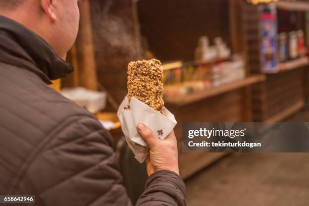 person is eating freshly baked trdelnik dessert cooking over an open flame in the streets of lviv ukraine - trdelník stock pictures, royalty-free photos & images