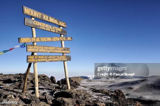 uhuru peak sign with northern icefield in the distance, kilimanjaro national park - berg kilimandscharo stock-fotos und bilder