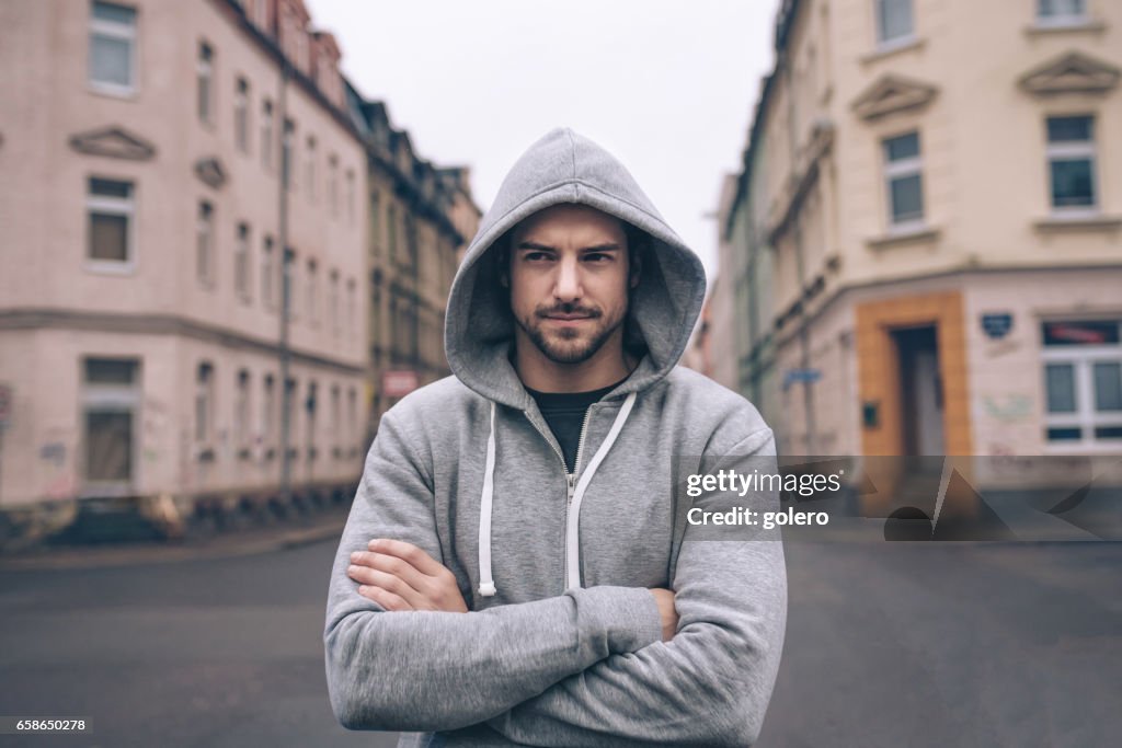 Porträtt av ung man i hoody i stadens gator