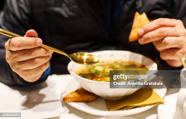 man eating vegetable minestrone soup - minestrone stock-fotos und bilder