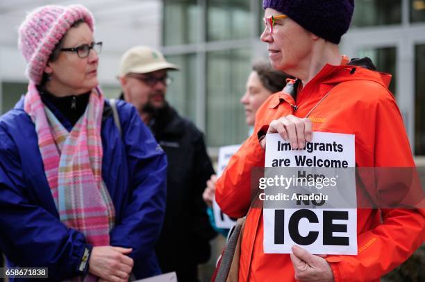 Woman holds a banner reading "Immigrants are welcome here - No ICE" during a protest outside the Immigration and Customs Enforcement building in...