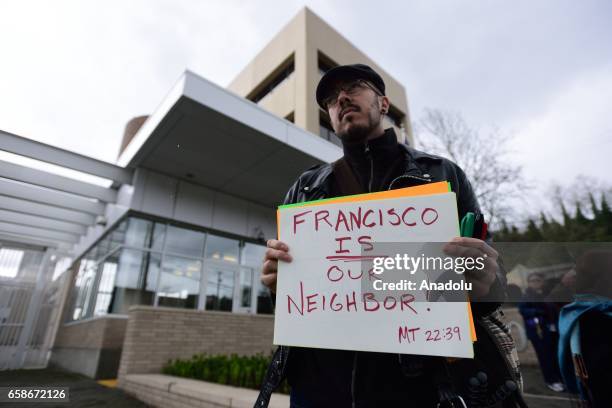 Man holds a banner reading "Francisco is our neighbor" during a protest outside the Immigration and Customs Enforcement building in Portland, Oregon,...