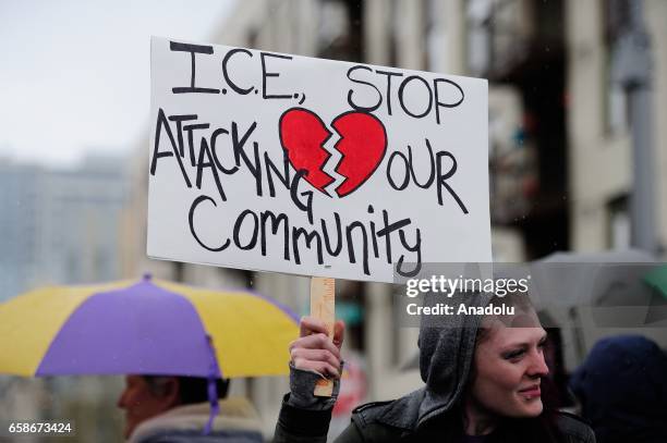 Woman holds a banner reading "I.C.E stop attacking our community" during a protest outside the Immigration and Customs Enforcement building in...
