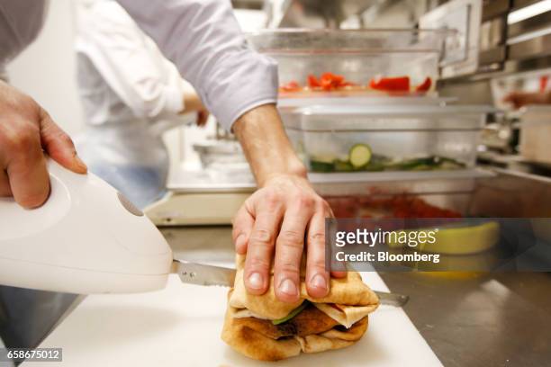 Chef cuts a freshly made sandwich wrap in the kitchen of a branch of food retailer Pret a Manger Ltd. In London, U.K., on Monday, March 27, 2017....