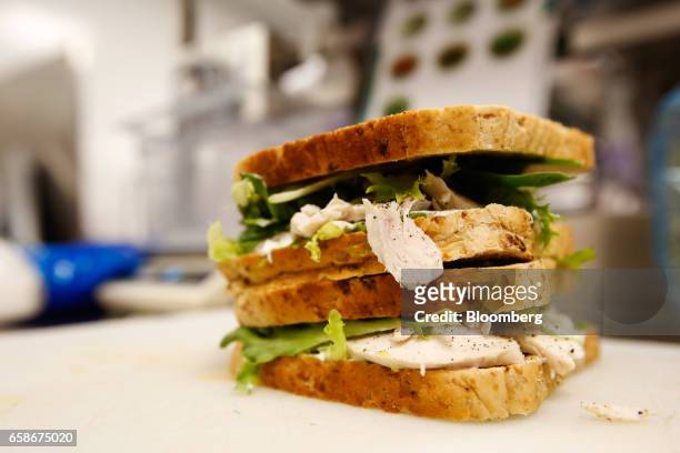 Filled sandwich sits on chopping board waiting to be sliced in the kitchen of a branch of food retailer Pret a Manger Ltd. In London, U.K., on...