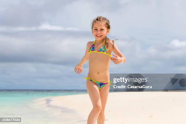 kleine mädchen spielen am sandstrand - young girl swimsuit stock-fotos und bilder