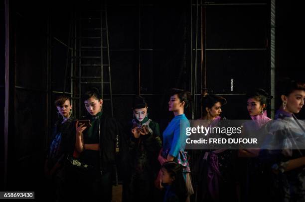 Models wait backstage before parading the Chantel Gong collection by Gong Hangyu during China Fashion Week in Beijing on March 28, 2017.