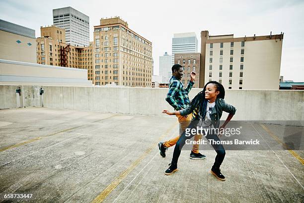 laughing couple dancing together on rooftop - leisure activity movement woman stock pictures, royalty-free photos & images