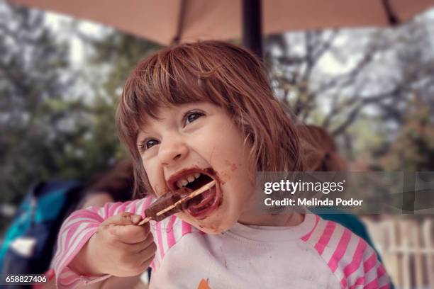 two-year old girl eating a popsicle - choclate photos et images de collection