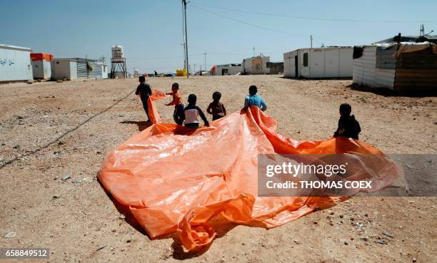 Syrian children play at the Zaatari camp which shelters some 80,000 Syrian refugees on the Jordanian border with war-ravaged Syria on March 28, 2017....