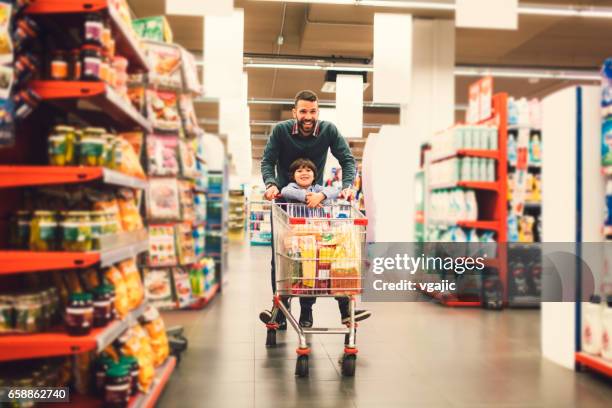 father and son in a supermarket. - shopping cart stock pictures, royalty-free photos & images