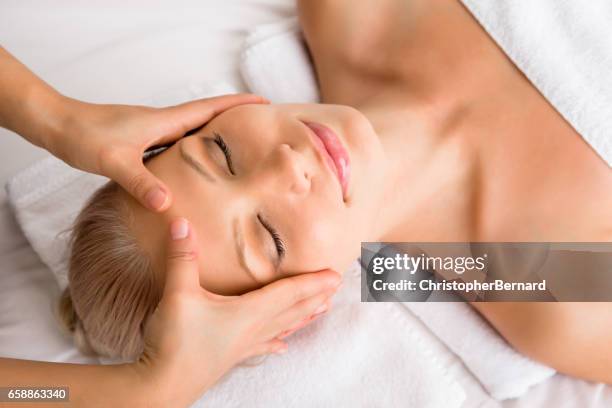 beautiful woman receiving head massage at spa - hand massage stock pictures, royalty-free photos & images