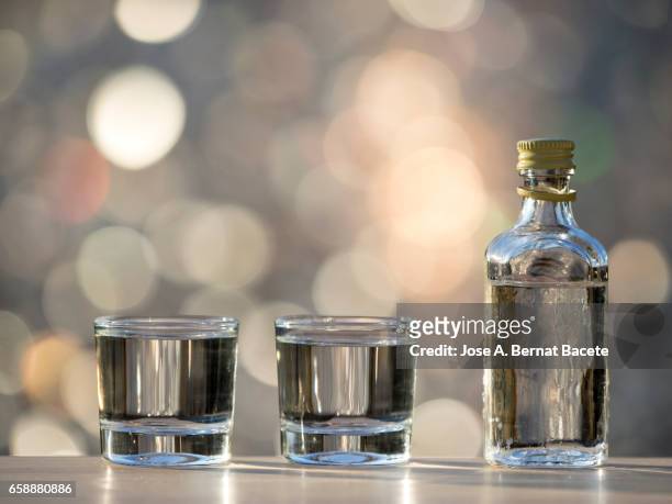 glass of crystal of chupito fill of an alcoholic liqueur  drink, illuminated by the light of the sun - alcoholismo photos et images de collection