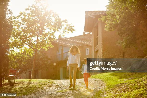 mother and son holding hands while walking in yard - sertão imagens e fotografias de stock