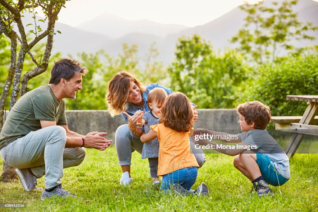Happy family playing with toddler on grassy field