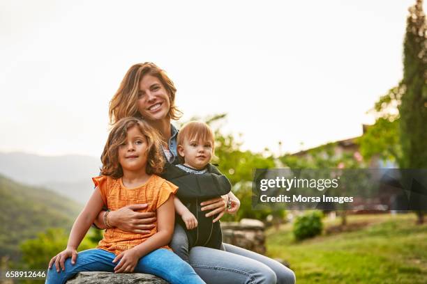 porträt von lächelnden mutter mit kinder am hof - familie mit zwei kindern stock-fotos und bilder