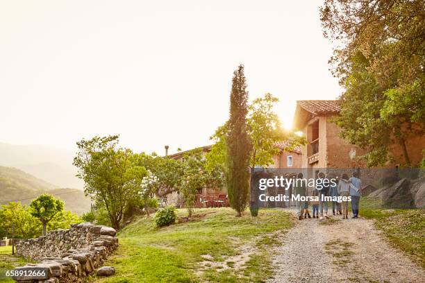 rear view of people walking towards houses - non urban scene stock pictures, royalty-free photos & images