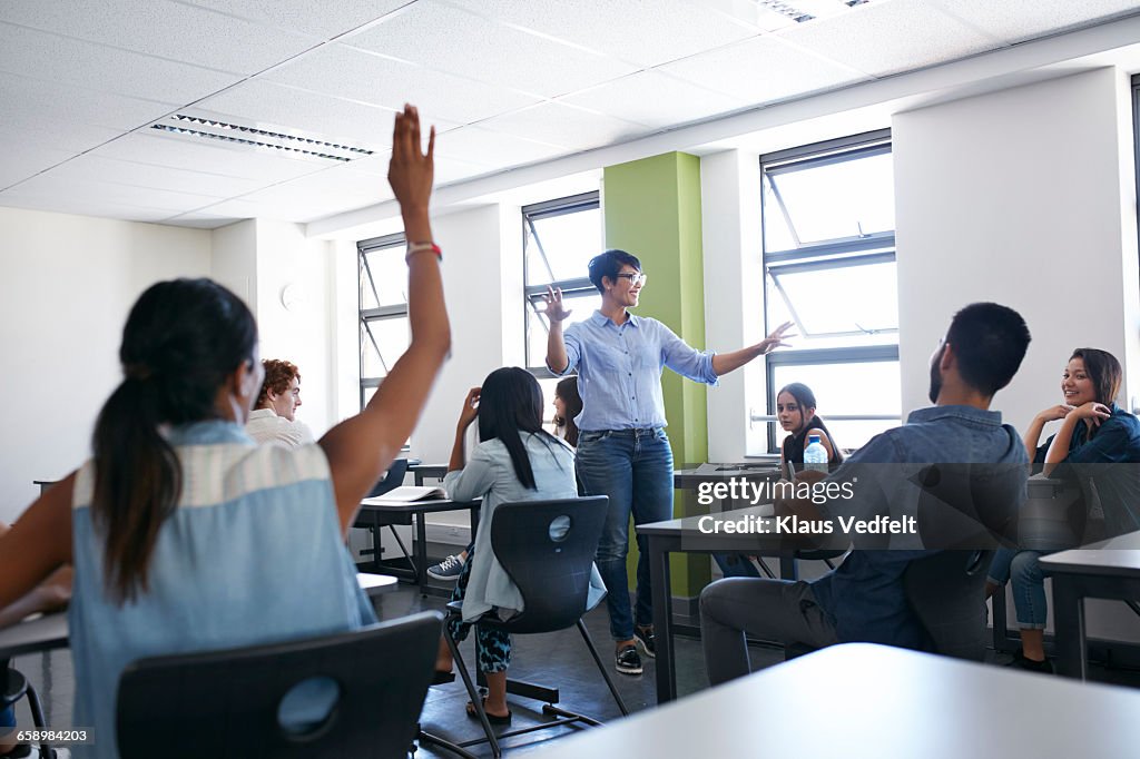 Teacher explaing to class,student with raised hand
