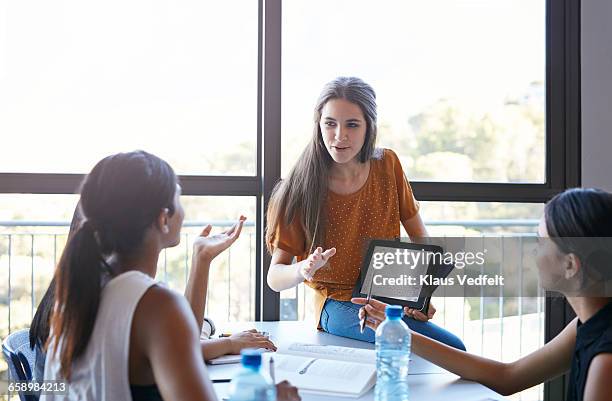 student presenting project on tablet to group - university girl stock-fotos und bilder