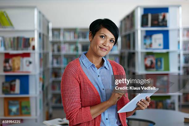 portrait of teacher holding tablet at library - librarian stock pictures, royalty-free photos & images