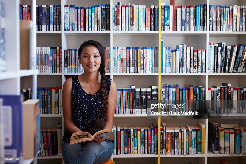 Female student holding book in library