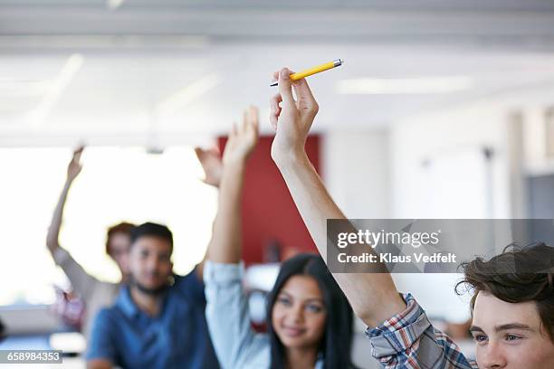 close-up of raised hands in classroom - holding pen in hand stock pictures, royalty-free photos & images