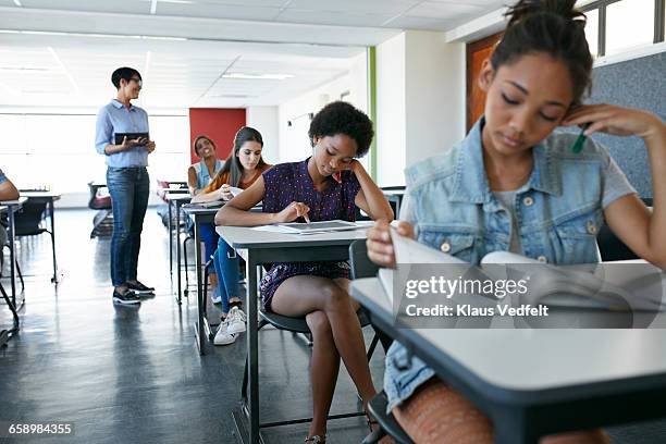 students looking in books and tablets in classroom - teenager reading a book stock pictures, royalty-free photos & images