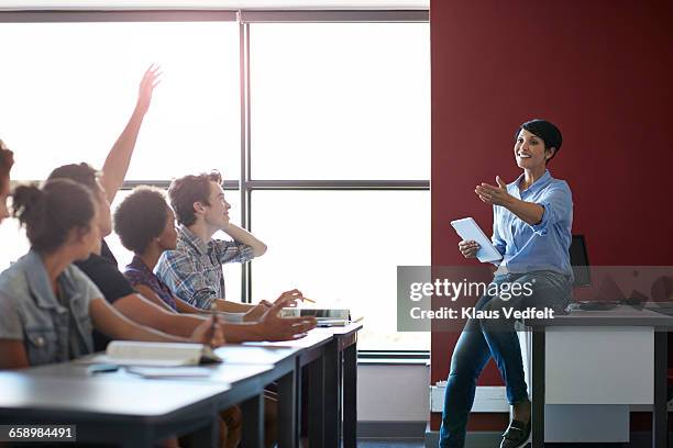 teacher pointing at student with raised hand - involvement stockfoto's en -beelden