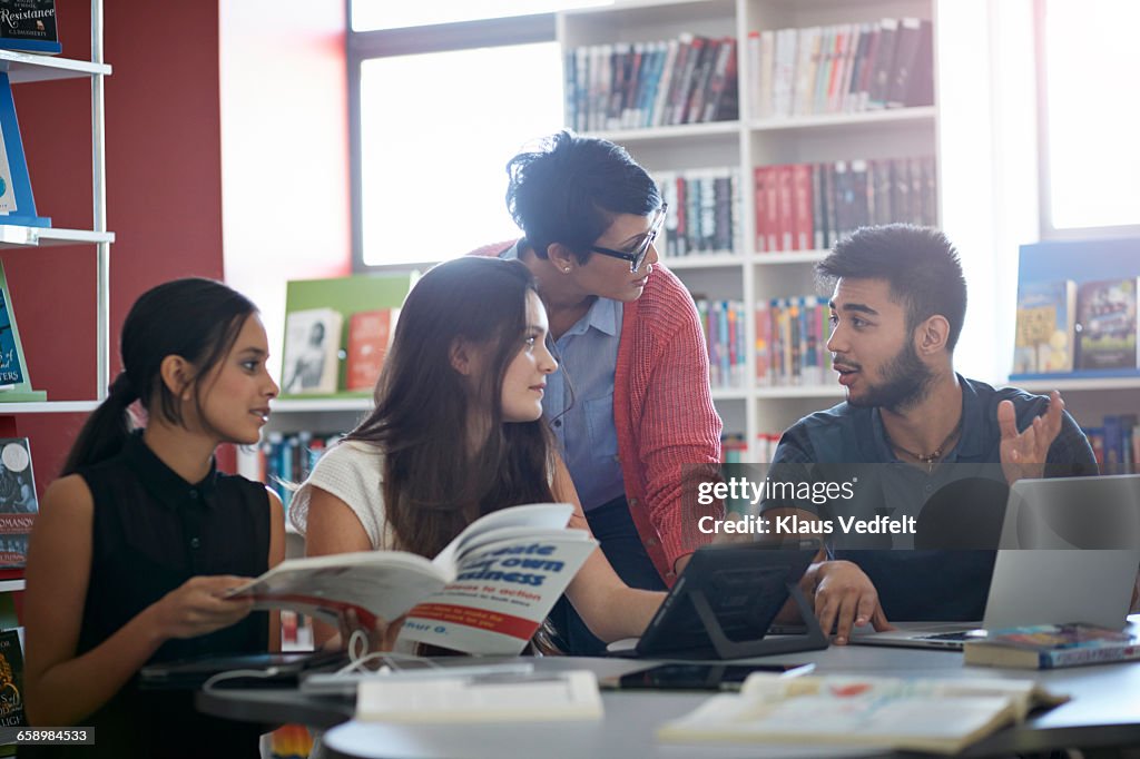 Teacher assisting students, in the library