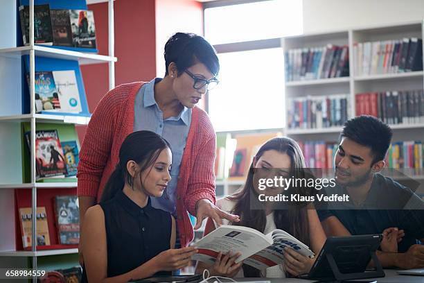 teacher assisting students, in the library - teenager reading a book stock pictures, royalty-free photos & images