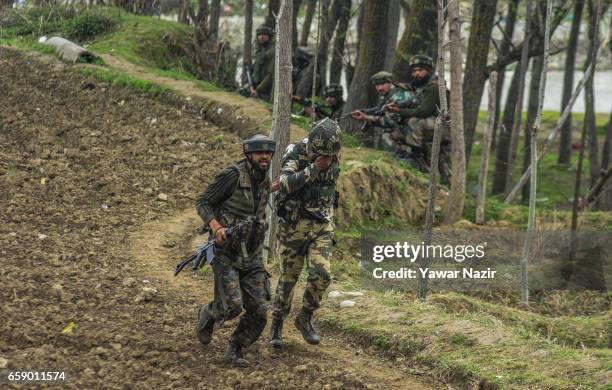 An Indian trooper rushes with his injured comrade who was during a gun battle between Indian government forces and suspected rebels on March 28, 2017...