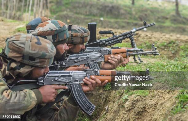 Indian army troopers aim their rifles towards a residential house where suspected rebels are trapped during a gun battle between Indian government...