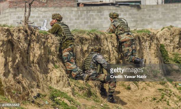 Indian government forces look towards a building being stormed by their comrades during a heavy exchange of fire between suspected rebels and Indian...