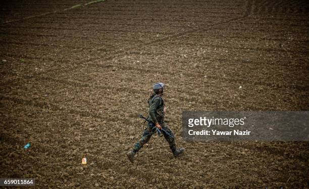 An Indian army trooper rushes towards gun battle site during a heavy exchange of fire between suspected rebels and Indian government forces during a...